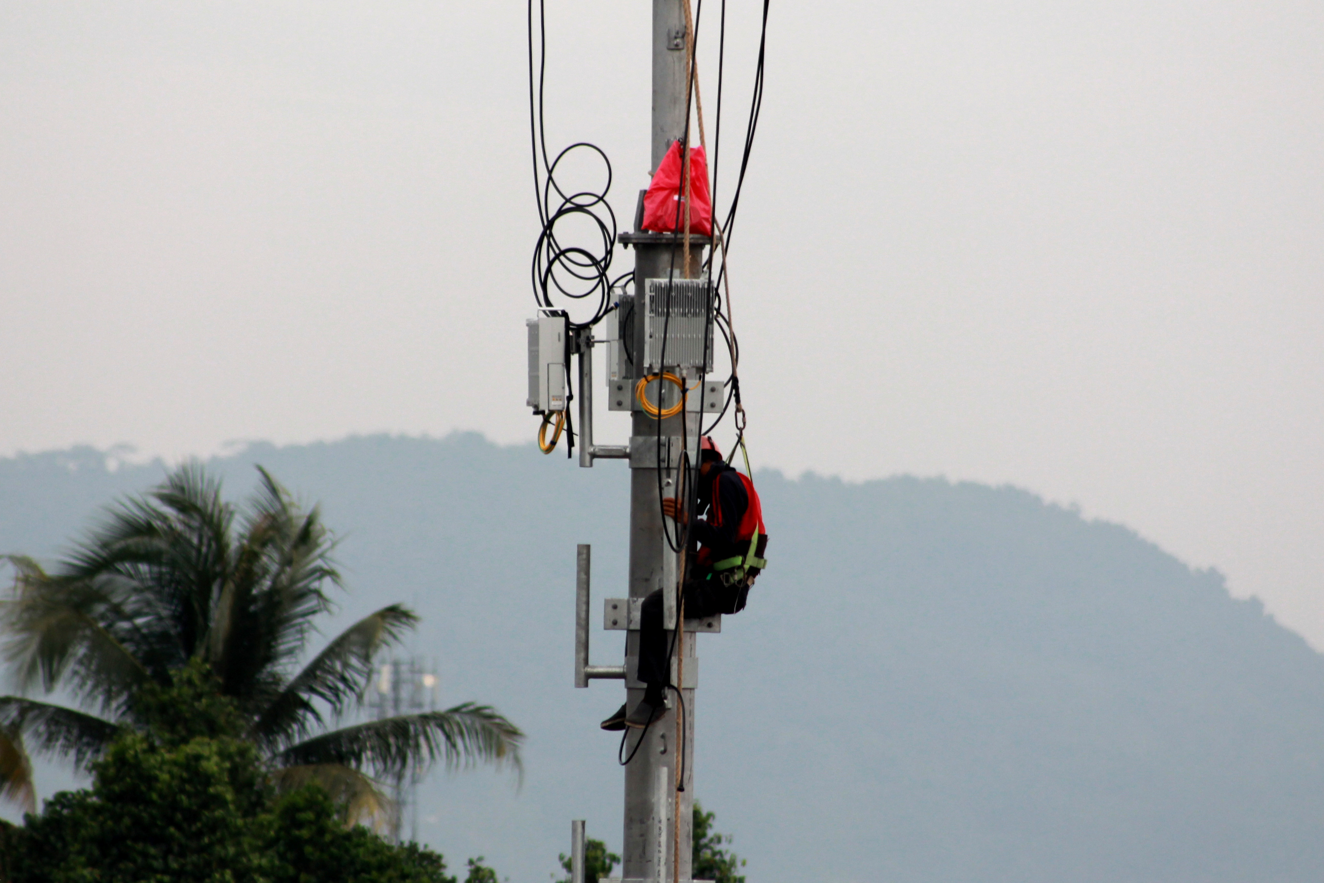 Seorang pekerja tengah memasang jaringan kabel pada menara Base Transceiver Station (BTS) bersama, Senin (6/2/2017) di Jalan Soekarno-Hatta, Tanjung Seneng, Bypass. (Foto: Lampungnews/El Shinta)