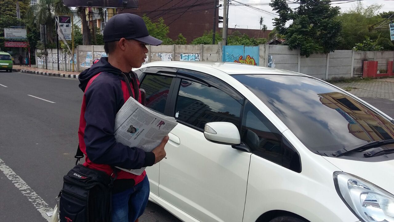 Zainal Abidin (34) penyandang tuna daksa yang menjadi loper koran di Tugu Adipura. (Lampungnews/Davit)
