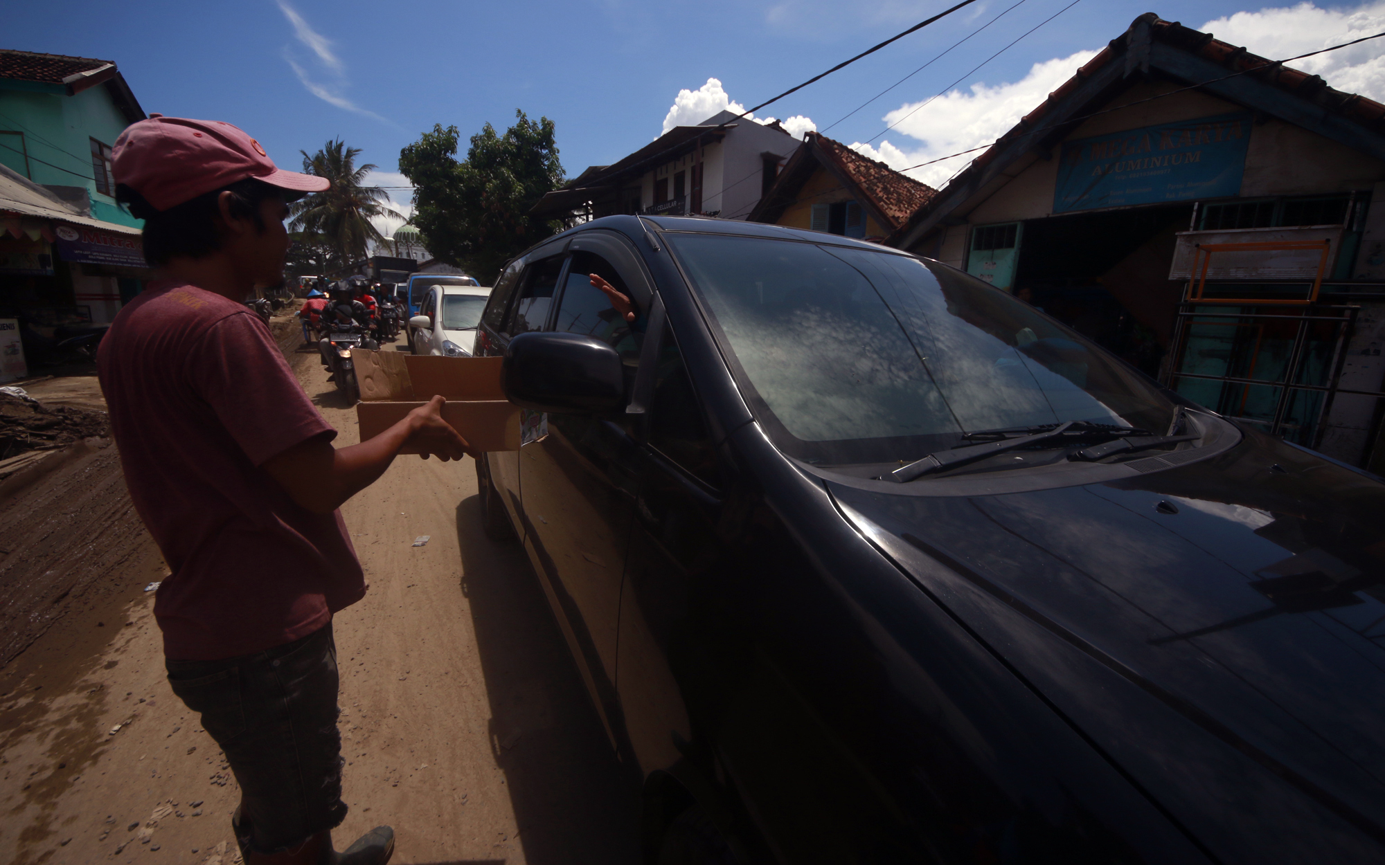 Seorang warga meminta sumbangan kepada para pengendara yang melintas di Jalan Ikan Sebelah, Telukbetung Selatan. Aksi ini dilakukan lantaran para korban banjir belum mendapatkan bantuan. (Lampungnews/El Shinta)