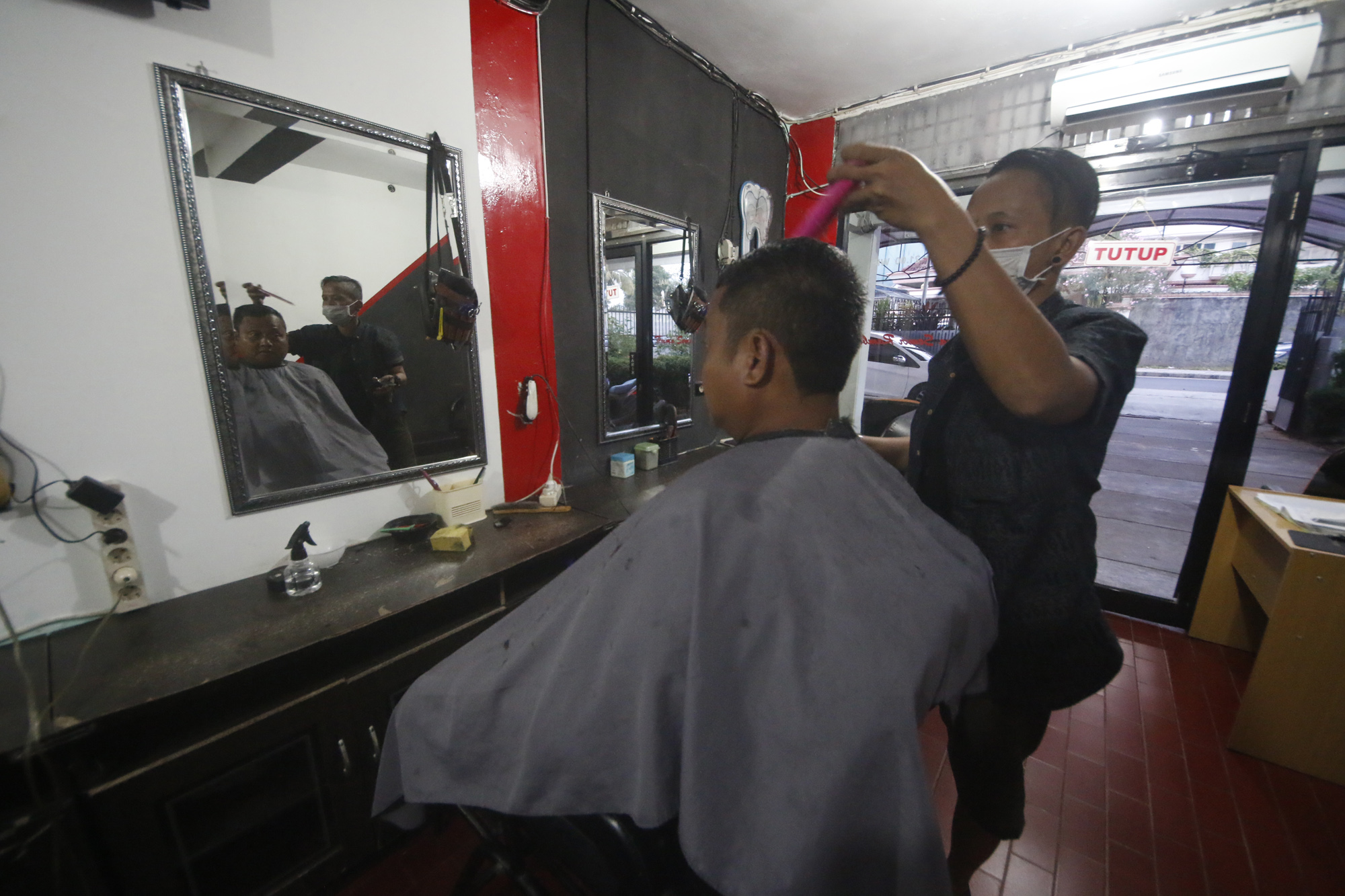 Seorang tukang cukur rambut tengah mencukur rambut pengunjung di salah satu barber shop. (Lampungnews/El Shinta)