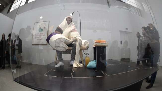 Seniman Prancis, Abraham Poincheval, sedang mengerami telur ayam di museum seni kontemporer Palais de Tokyo, Paris pada 29 Maret lalu (AFP/Stephane de Sakutin].