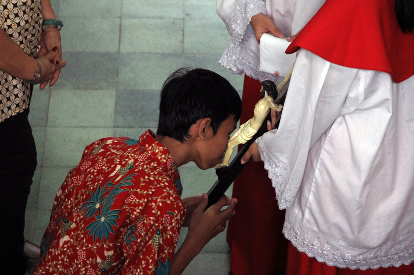 Seorang umat melakukan upacara penghormatan salib dengan mencium tubuh Yesus yang tergantung di kayu salib dalam Ibadat Jumat Agung di Gereja Katedral Kristus Raja, Jumat (14/04). (Lampungnews/El Shinta)