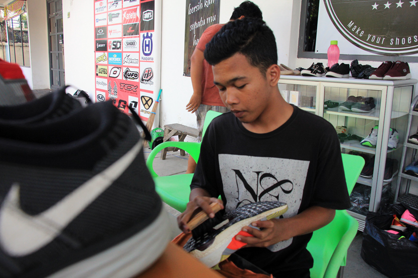 Seorang petugas tengah menyikat bagian bawah sepatu dengan menggunakan sikat dan cleaner khusus. (Lampungnews/El Shinta)
