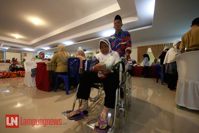 Petugas membantu mendorong kursi roda salah satu calhaj kloter pertama asal Lampung Tengah, Minggu (30/7). Calhaj yang menggunakan  kursi roda biasanya kondisinya sudah tidak memungkinkan untuk berjalan kaki. (Lampungnews/El Shinta)