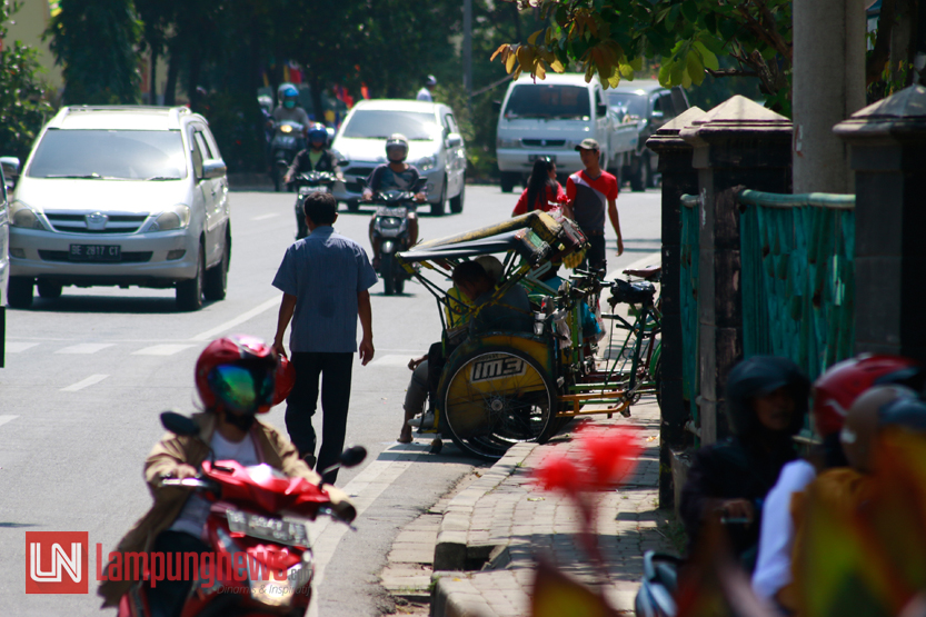 Sejumlah pejalan kaki memilih berjalan di jalan lantaran trotoar di Jalan Teuku Umar justru digunakan untuk parkir becak, Jumat (4/8). Belakangan ini hak pejalan kaki di Bandarlampung perlahan menghilang seiring beralihnya fungsi trotoar yang digunakan oleh sejumlah pihak untuk kepentingannya pribadi. (Lampungnews/El Shinta)
