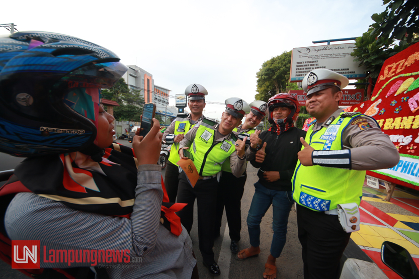 Seorang pengendara motor mengajak foto para petugas Satlantas Polresta Bandarlampung setelah mampu menunjukkan kelengkapan surat berkendaranya pada gelaran Protap Sore di Jalan Raden Intan, Selasa (10/10). (Lampungnews/El Shinta)