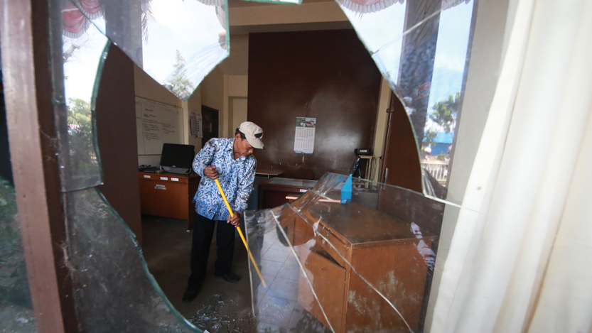 Pegawai membersihkan pecahan kaca jendela Dinas Pemuda dan Olahraga yang dirusak orang tak dikenal, Jumat (10/11). (Lampungnews.com/El Shinta)