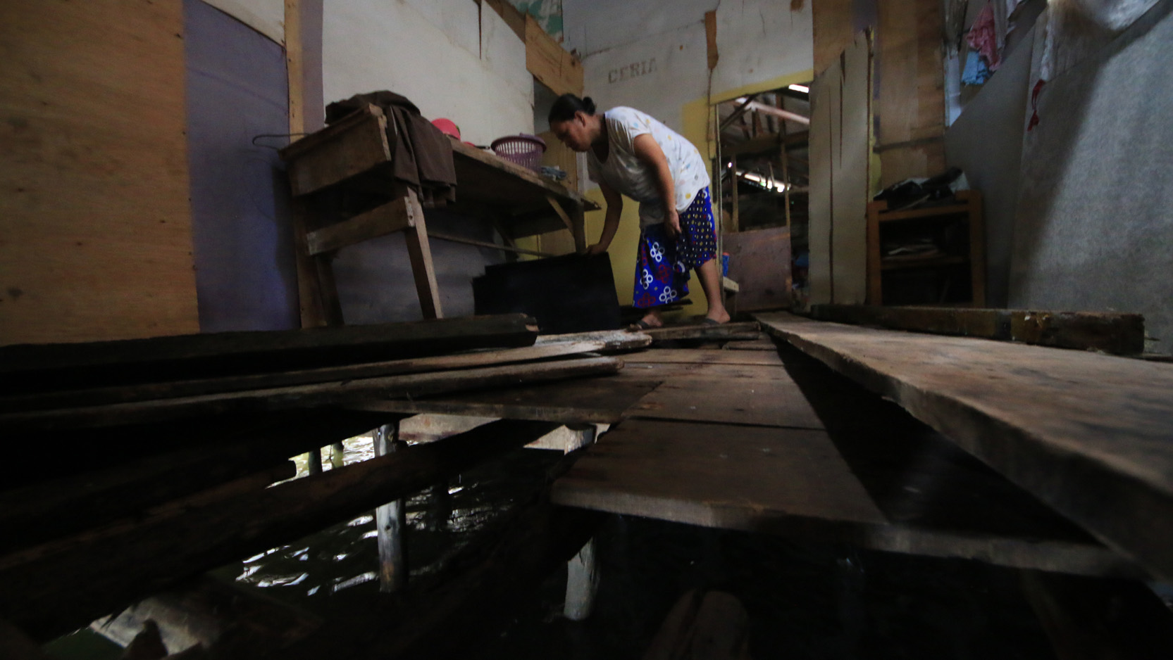 Karni membereskan perabotan yang berada di rumah miliknya yang rusak diterjang keganasan ombak pada Selasa (5/12) malam. (Lampungnews.com/El Shinta)